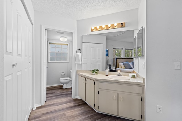 bathroom with toilet, a textured ceiling, hardwood / wood-style flooring, and vanity