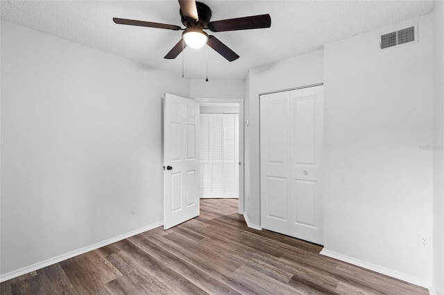 unfurnished bedroom with ceiling fan, a closet, a textured ceiling, and wood-type flooring