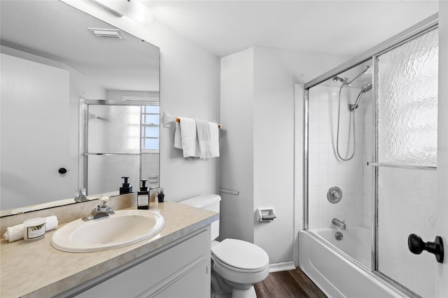 full bathroom featuring hardwood / wood-style flooring, bath / shower combo with glass door, toilet, and vanity