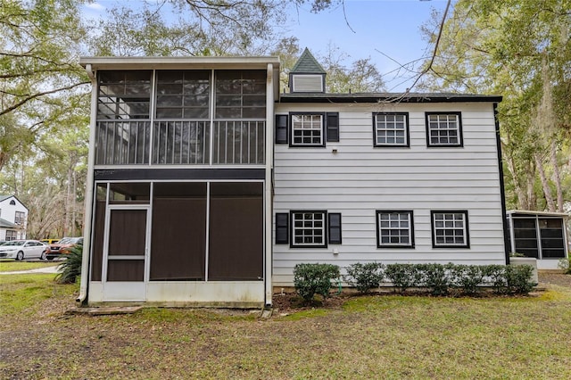 back of house with a sunroom and a lawn