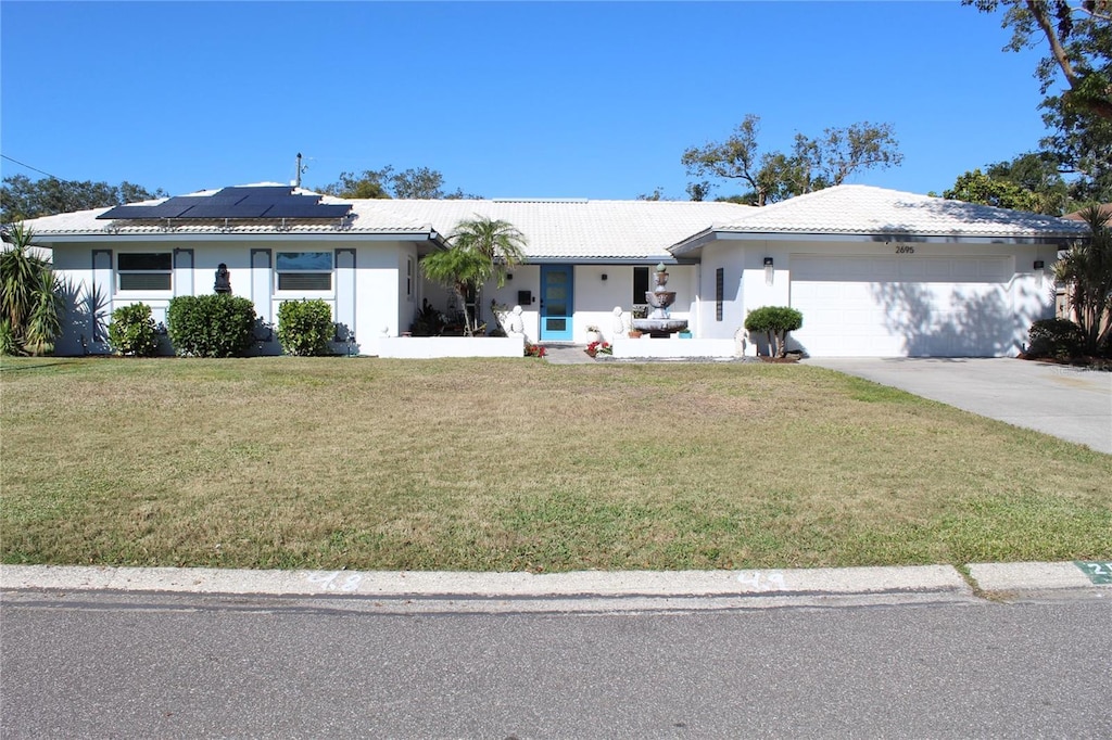 ranch-style house featuring solar panels, a garage, and a front lawn