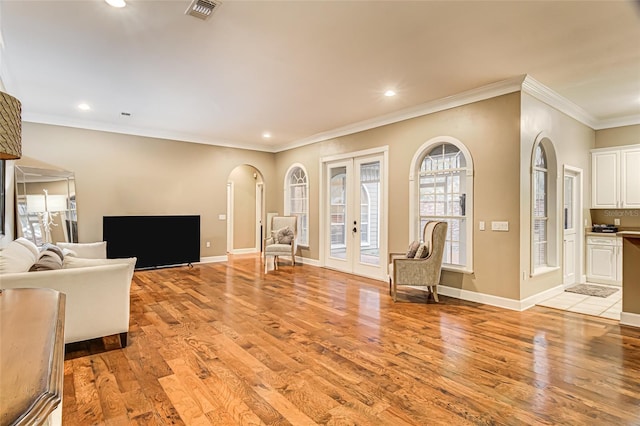 unfurnished living room featuring french doors, crown molding, and light hardwood / wood-style flooring