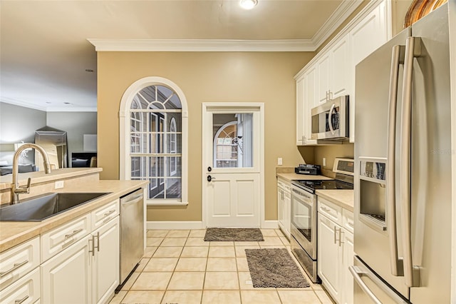 kitchen featuring light tile patterned flooring, sink, white cabinetry, ornamental molding, and stainless steel appliances