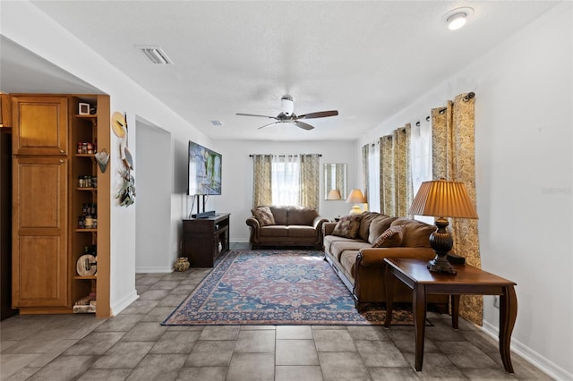 living room with a textured ceiling and ceiling fan