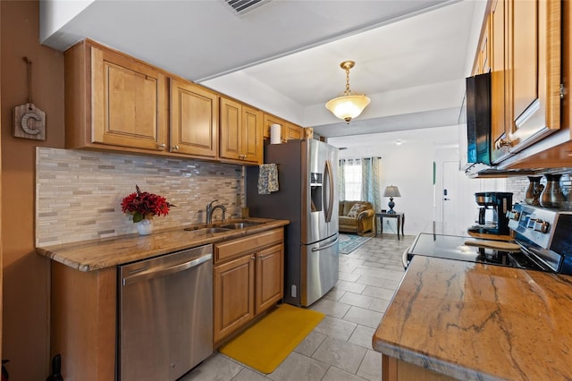 kitchen featuring pendant lighting, stainless steel appliances, sink, and backsplash