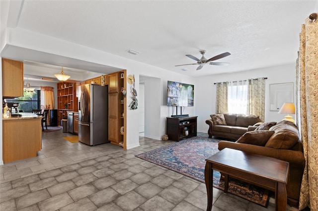 living room featuring ceiling fan and a textured ceiling