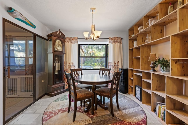 tiled dining area featuring an inviting chandelier and a textured ceiling