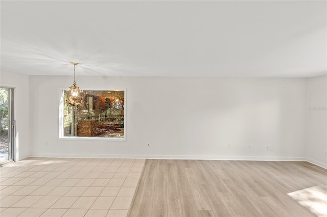 spare room featuring an inviting chandelier and light wood-type flooring