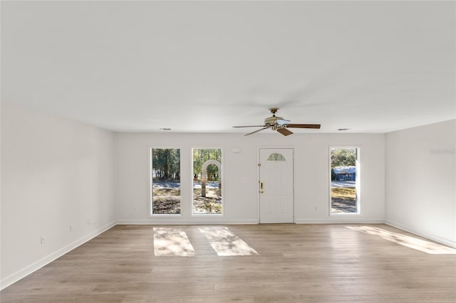 empty room featuring light hardwood / wood-style floors, ceiling fan, and a healthy amount of sunlight