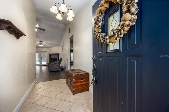 tiled foyer with lofted ceiling and ceiling fan with notable chandelier