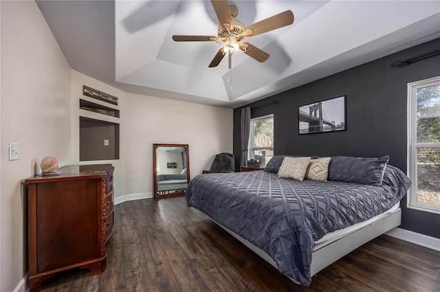 bedroom featuring dark hardwood / wood-style flooring, a tray ceiling, and ceiling fan