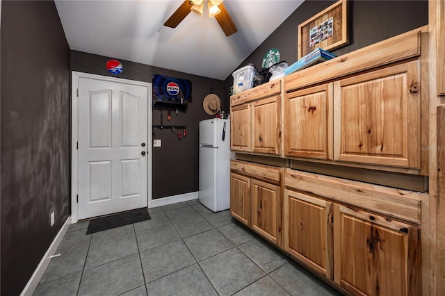 interior space featuring white refrigerator, ceiling fan, tile patterned flooring, and vaulted ceiling