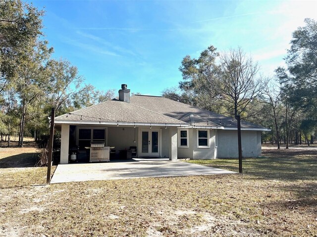 rear view of house with a patio, a lawn, and french doors