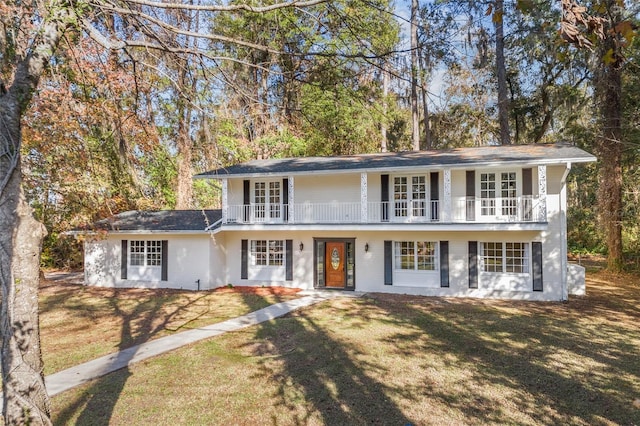 view of front of home featuring a balcony, a front lawn, and french doors