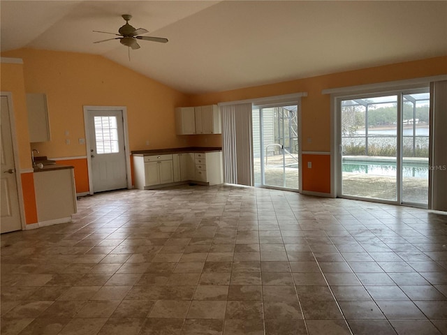 unfurnished living room featuring vaulted ceiling and ceiling fan