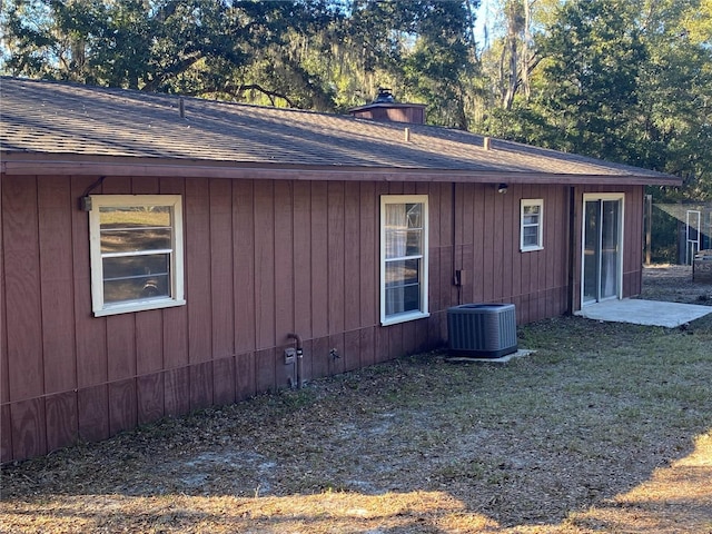 view of side of home with central air condition unit and a lawn