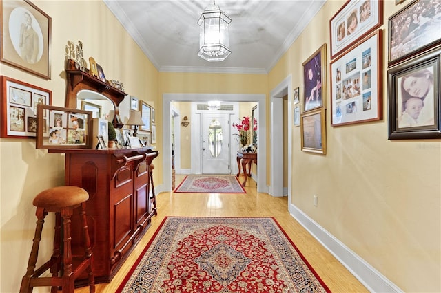 entrance foyer with a notable chandelier, ornamental molding, and light wood-type flooring