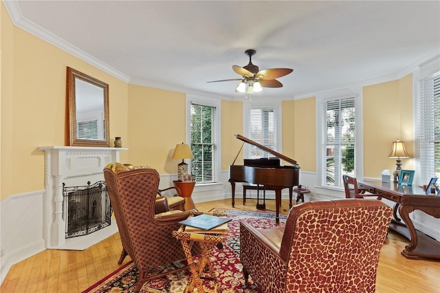 living area with ornamental molding, light hardwood / wood-style floors, and ceiling fan