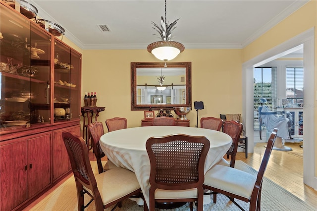 dining space featuring crown molding and light wood-type flooring