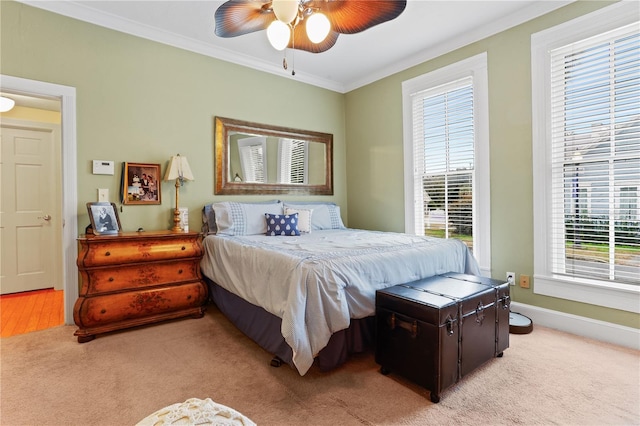 carpeted bedroom featuring ceiling fan, ornamental molding, and multiple windows