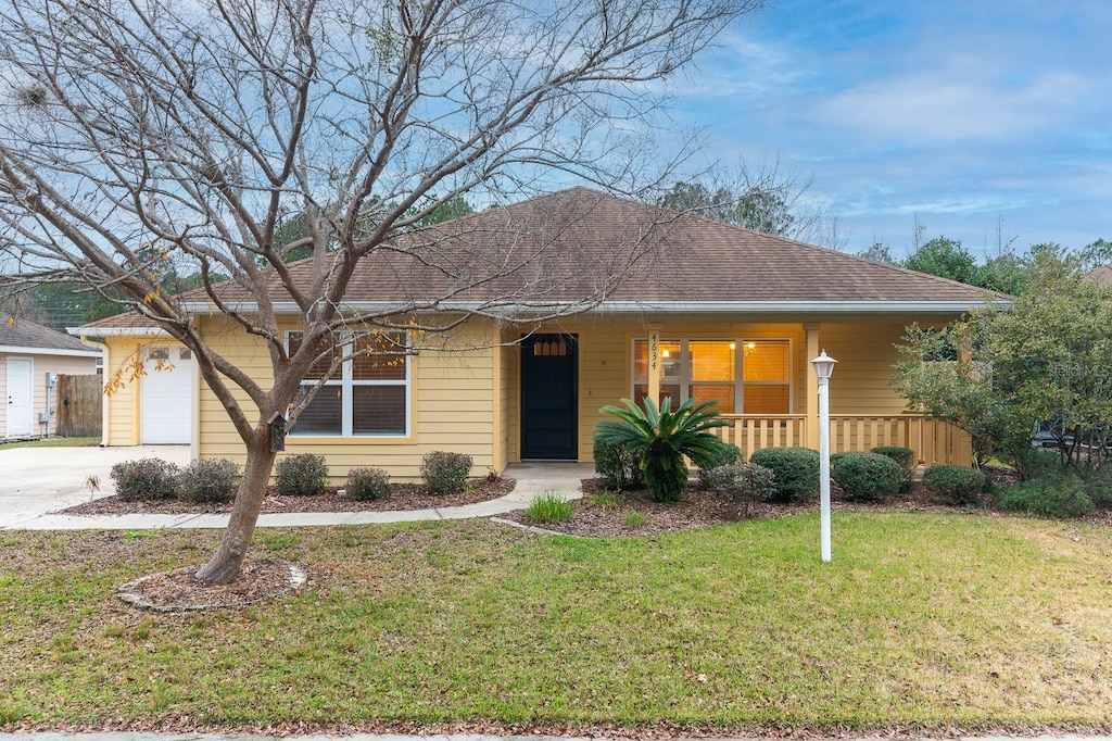 single story home featuring a porch, a garage, and a front lawn