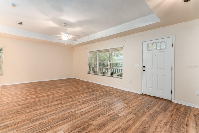 foyer entrance with hardwood / wood-style floors, a tray ceiling, and ceiling fan