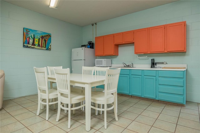 kitchen with light tile patterned floors, white appliances, and sink