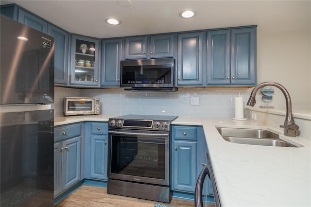 kitchen featuring sink, backsplash, stainless steel appliances, and blue cabinetry