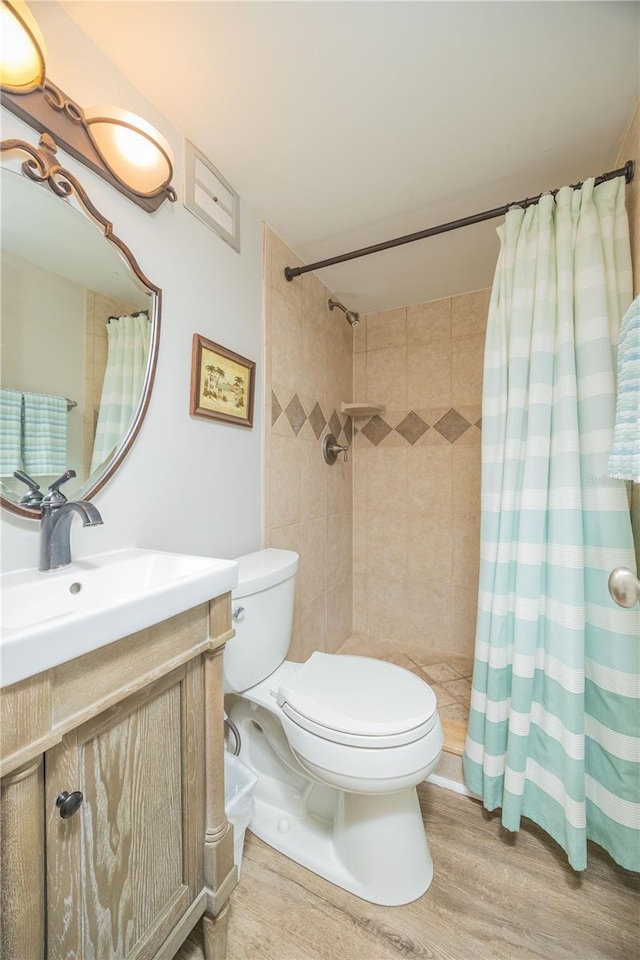 bathroom with hardwood / wood-style flooring, vanity, toilet, and curtained shower