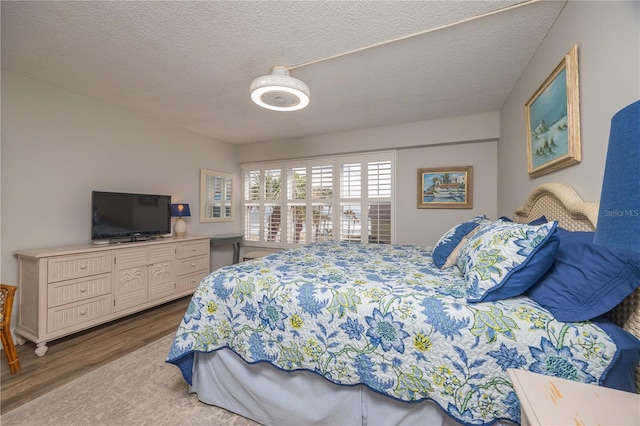 bedroom with ceiling fan, hardwood / wood-style flooring, and a textured ceiling