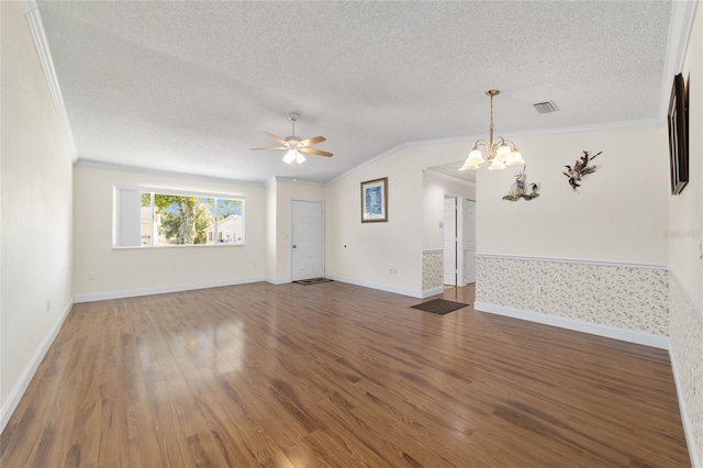 unfurnished living room with hardwood / wood-style floors, ceiling fan with notable chandelier, lofted ceiling, ornamental molding, and a textured ceiling