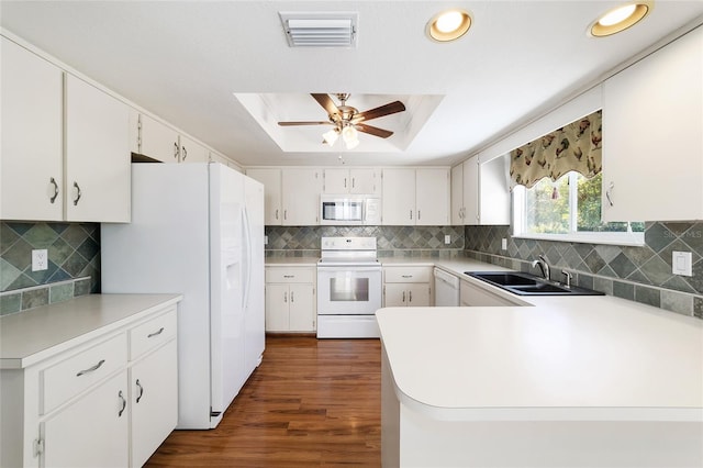 kitchen featuring white cabinetry, sink, white appliances, and a tray ceiling