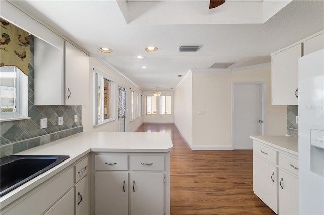 kitchen featuring backsplash, dark hardwood / wood-style floors, kitchen peninsula, and white cabinets