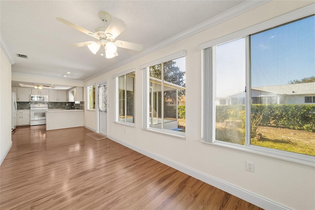 unfurnished sunroom featuring ceiling fan