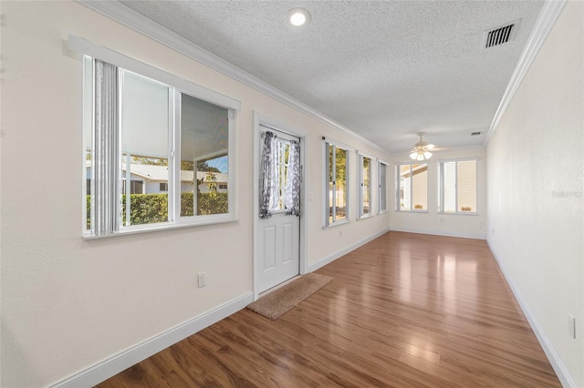 interior space featuring hardwood / wood-style flooring, ornamental molding, ceiling fan, and a textured ceiling