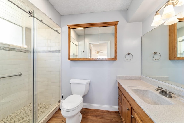 bathroom with a shower with shower door, hardwood / wood-style flooring, vanity, toilet, and a textured ceiling