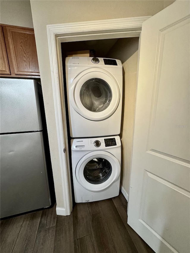 laundry area with dark wood-type flooring and stacked washing maching and dryer