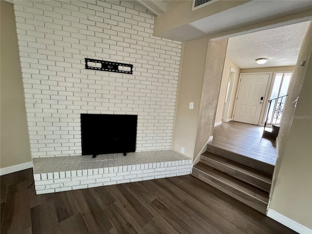 unfurnished living room featuring beamed ceiling, dark hardwood / wood-style floors, and a textured ceiling