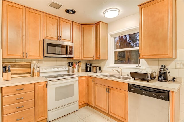 kitchen featuring light tile patterned flooring, light brown cabinetry, tasteful backsplash, sink, and stainless steel appliances