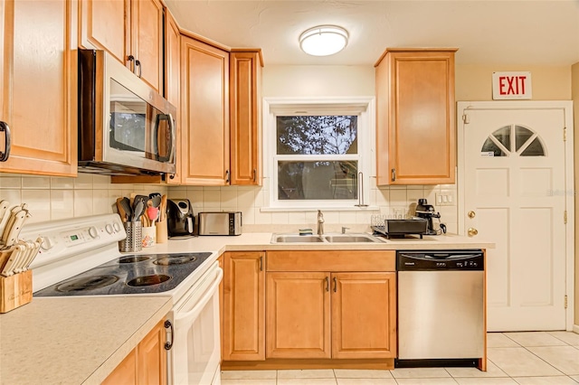 kitchen with stainless steel appliances, sink, light tile patterned floors, and decorative backsplash