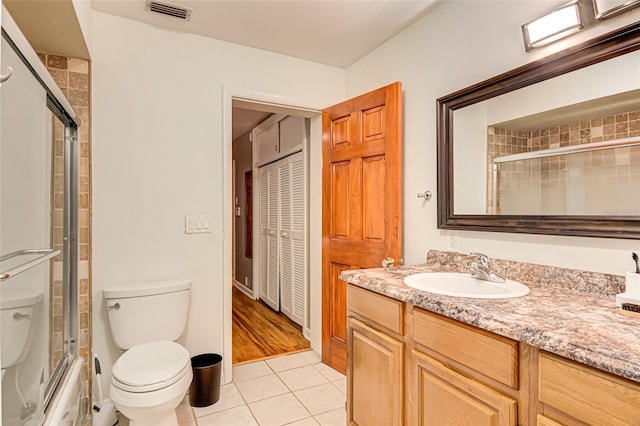 full bathroom featuring bath / shower combo with glass door, vanity, toilet, and tile patterned flooring