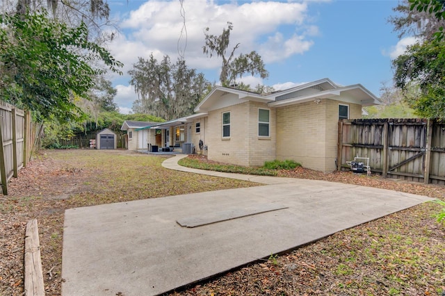 back of house with a storage shed and a lawn