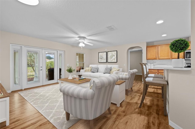 living room with ceiling fan, light hardwood / wood-style floors, and french doors