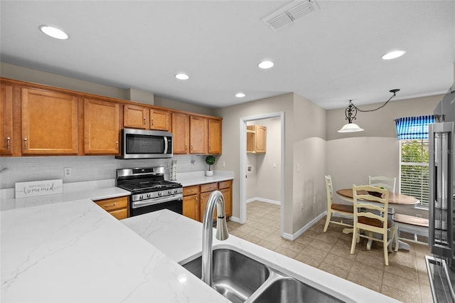 kitchen with light stone countertops, appliances with stainless steel finishes, decorative backsplash, and decorative light fixtures