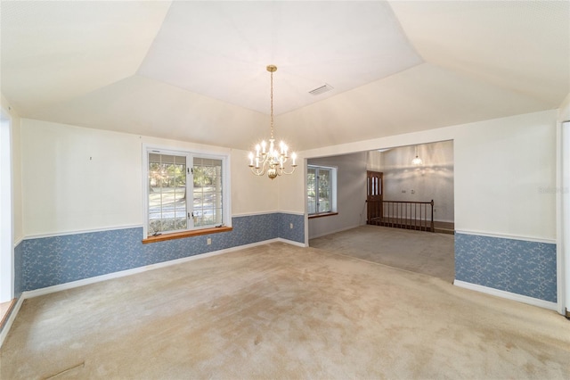 carpeted empty room featuring a notable chandelier, a wealth of natural light, and vaulted ceiling