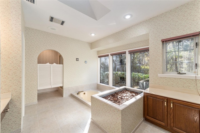 bathroom with tile patterned flooring, vanity, and a relaxing tiled tub