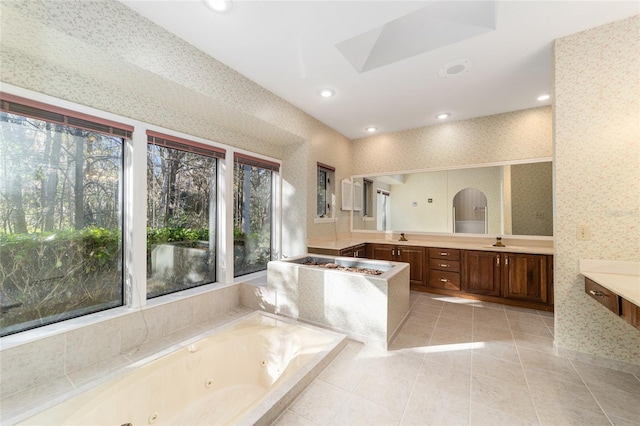 bathroom with tiled tub, sink, and tile patterned floors