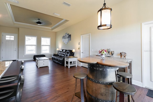 dining space with dark hardwood / wood-style floors, ceiling fan, ornamental molding, and a tray ceiling