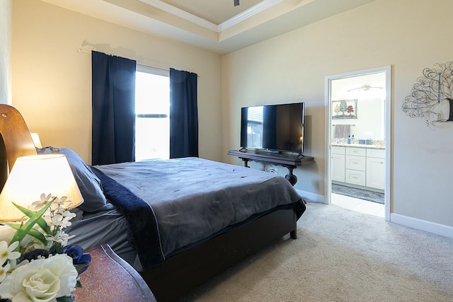 bedroom featuring a raised ceiling, ornamental molding, connected bathroom, and light colored carpet