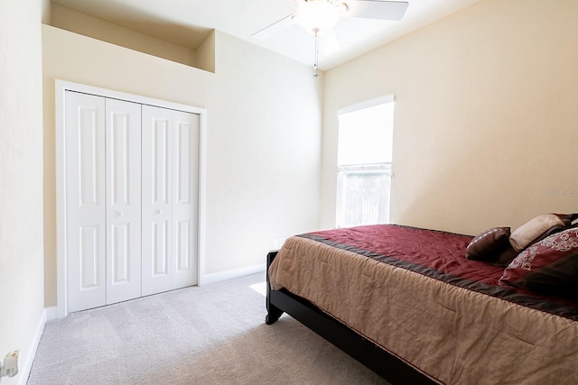 bedroom featuring light colored carpet, ceiling fan, and a closet